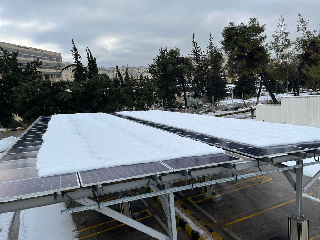 Snow-covered solar carpark PV modules at University of Jordan